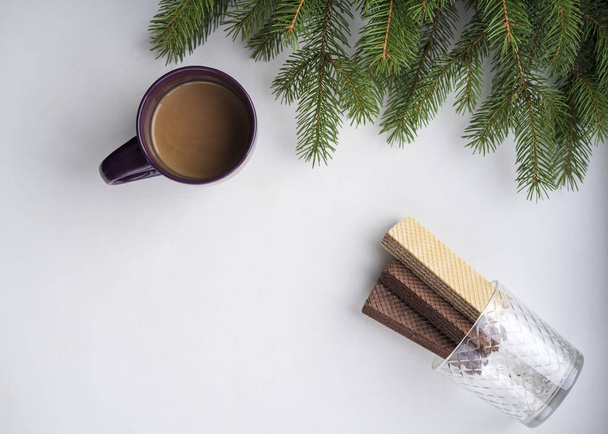 sobre un fondo blanco ramas de abeto verde sin juguetes de Navidad, una taza de café y galletas dulces, vista horizontal, espacio para copiar
 - Foto, imagen