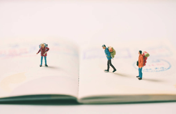 Miniature people figures with backpack walking and standing on p - 写真・画像