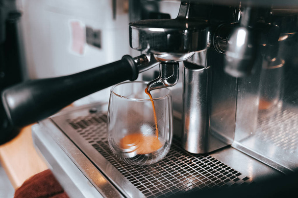 O espresso perfumado flui de uma máquina de café para uma xícara. Fazendo café aromático com equipamento de café profissional
 - Foto, Imagem