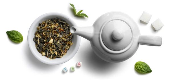 Зеленый чай с натуральными ароматическими добавками и чайник. Вид сверху на белый фон
 - Фото, изображение