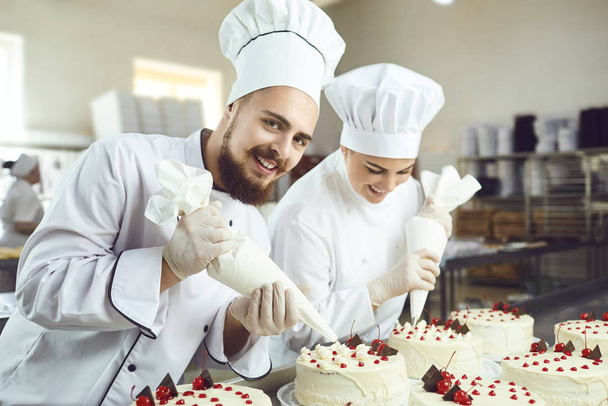 Confectioners with a bag for the cream will decorate the cake. - Фото, зображення