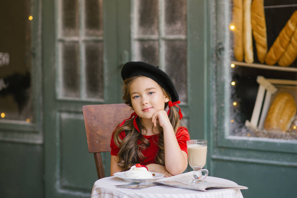 mooi zes-jarige meisje in een rood fluwelen jurk en een zwarte be - Foto, afbeelding