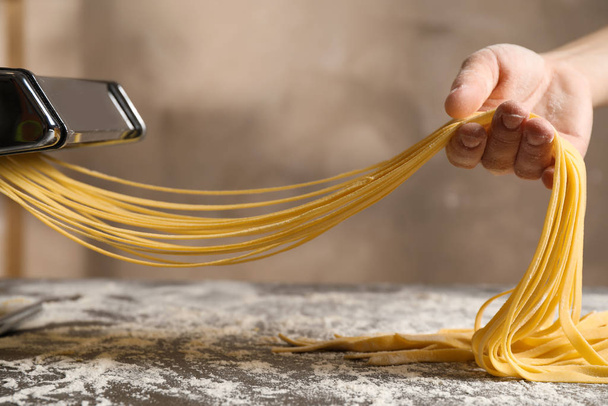 Nainen, joka valmistaa nuudeleita pastakoneen kanssa pöydässä, sulje
 - Valokuva, kuva