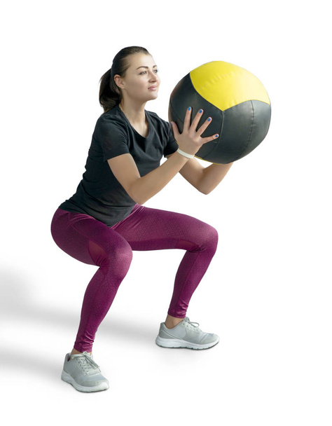 Beautiful sporty woman doing squats with med ball. Photo of muscular fitness model isolated on white background. Fitness and healthy lifestyle concept - Fotografie, Obrázek