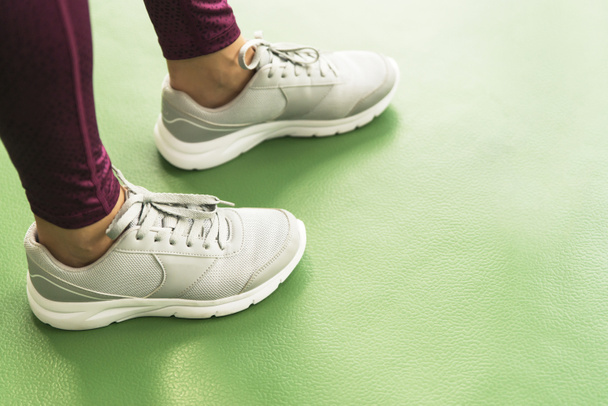 Close up view of womans legs wearing sneakers in the gym with copy space - Foto, afbeelding