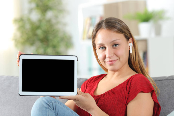 Satisfied woman with earbuds showing tablet screen - Foto, immagini