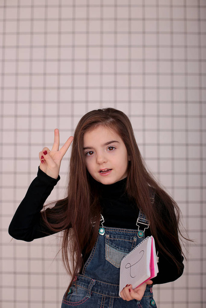jeune fille souriante de huit ans avec les cheveux longs dans un col roulé noir et robe de soleil en denim avec un signe "2 deux
" - Photo, image