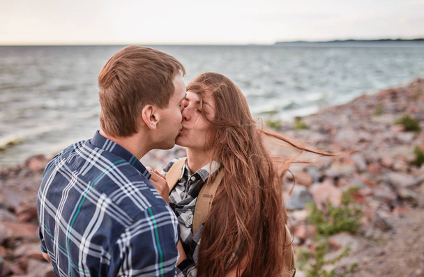 κομψό hipster ζευγάρι φιλιά στη λίμνη. άνδρας και γυναίκα αγκαλιάζει, στην αγάπη χαλάρωση στο πάρκο καλοκαίρι, ημερομηνία πικνίκ. - Φωτογραφία, εικόνα