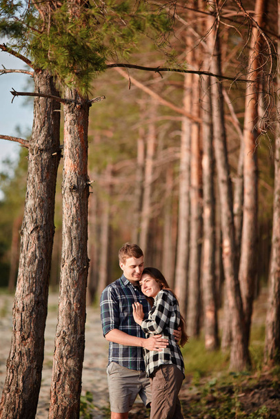 森でロマンチックなデート中にお互いに笑みを浮かべて若いカップル - 写真・画像