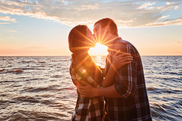 Pár szerelmeseinek csókolózás vízbe naplementekor - Fotó, kép