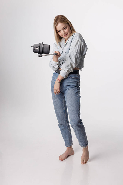 счастливая девушка делает автопортрет со смартфоном, прикрепленным к палке для селфи
 - Фото, изображение