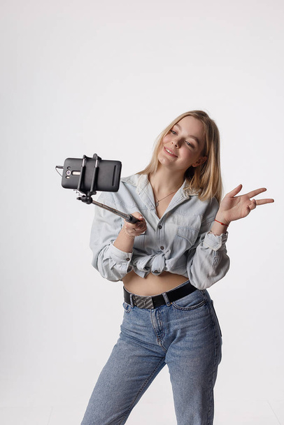 счастливая девушка делает автопортрет со смартфоном, прикрепленным к палке для селфи
 - Фото, изображение