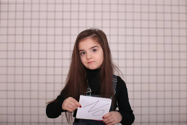 giovane ragazza arrabbiata di otto anni con i capelli lunghi in un dolcevita nero e denim prendisole con il segno "NO
" - Foto, immagini