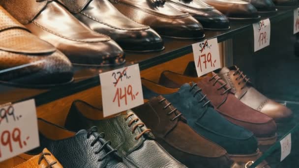 Ayakkabı mağazasının vitrininde farklı renkte deri erkek ayakkabıları ve indirimli fiyat etiketleri olan raflar. - Video, Çekim