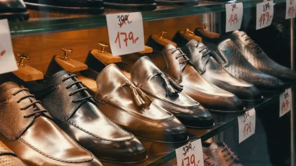Ayakkabı mağazasının vitrininde farklı renkte deri erkek ayakkabıları ve indirimli fiyat etiketleri olan raflar. - Video, Çekim