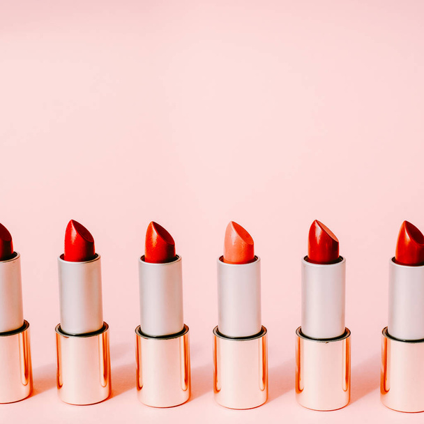 Multi-colored lipsticks stand in a row on a pink background. The concept of different, collections and beauty. Red, pink and burgundy lipsticks - Fotó, kép