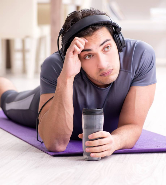 Чоловік займається спортом вдома і слухає музику
 - Фото, зображення