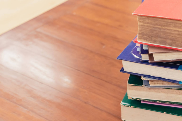 Lehrbuchstapel auf Holztisch mit unscharfem Hintergrund in der Universitätsbibliothek mit Kopierraum. Foto Konzept der Bildung Wissen und Lernen. Selektiver Fokus - Foto, Bild