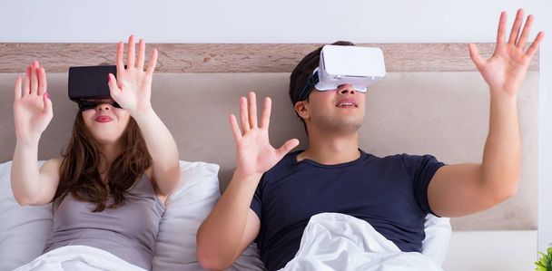 ベッドの中に仮想現実ゴーグル付きの妻と夫 - 写真・画像