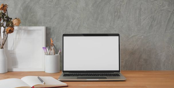 Обрізаний знімок модного робочого місця з макетним ноутбуком та офісними приладдям на дерев'яному столі та сірому фоні стіни
  - Фото, зображення