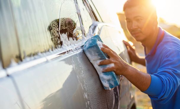 Asian man using blue sponge with soap to washing the car at outd - Foto, Bild
