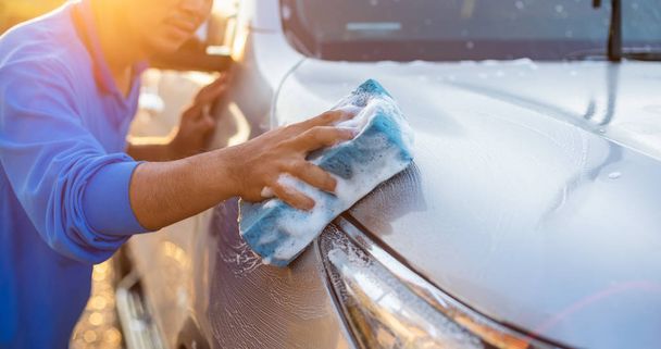 Aziatisch man met behulp van blauwe spons met zeep naar wassen van de auto op outd - Foto, afbeelding