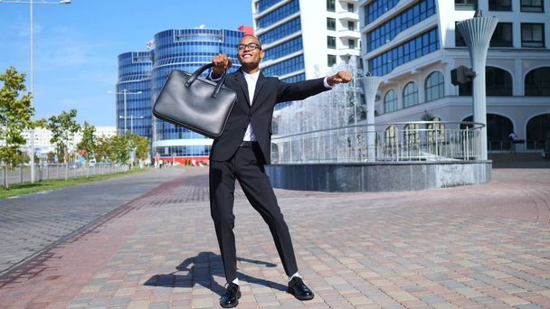 Jeune homme d'affaires multiracial en costume noir dansant en plein air
 - Photo, image