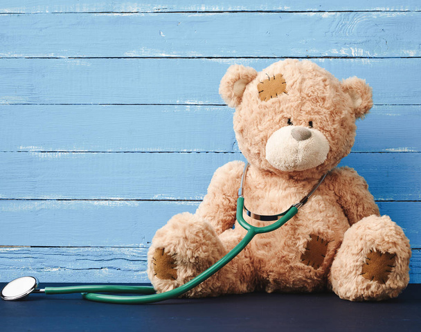teddy bear is sitting, green stethoscope is hanging on his neck - Photo, Image