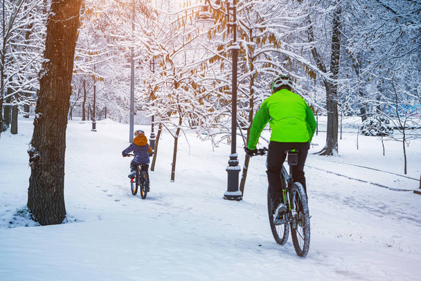 A father and his son ride a bikes in a winter park - Photo, Image
