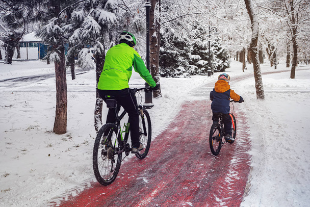 L'homme et son fils font du vélo le long d'une piste cyclable dans un parc d'hiver
 - Photo, image