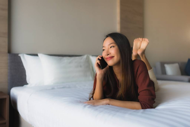 Portrait belles jeunes femmes asiatiques en utilisant le téléphone mobile sur le lit
 - Photo, image