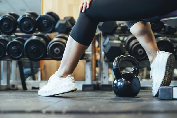 Detail of a girl's feet sitting in the gym with a kettlebell on  - Photo, Image