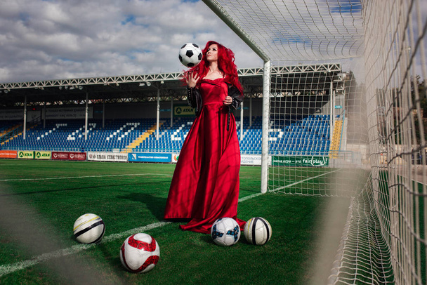Luxueuse femme aux cheveux roux et dans une robe rouge joue sur le fo
 - Photo, image