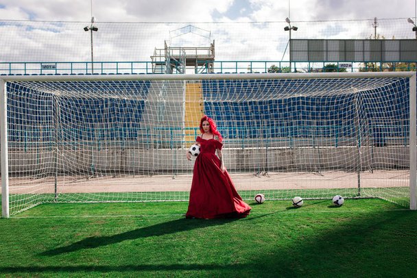 Luxe vrouw met rood haar en in een rode jurk speelt op de fo - Foto, afbeelding