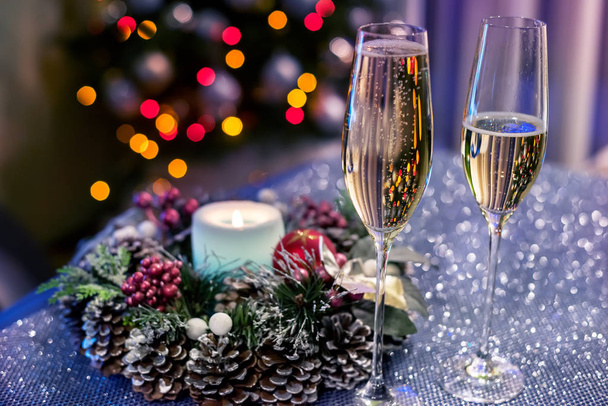 Bicchieri con champagne sullo sfondo di un albero di Natale sotto le luci. Home magica serata atmosfera festiva
. - Foto, immagini