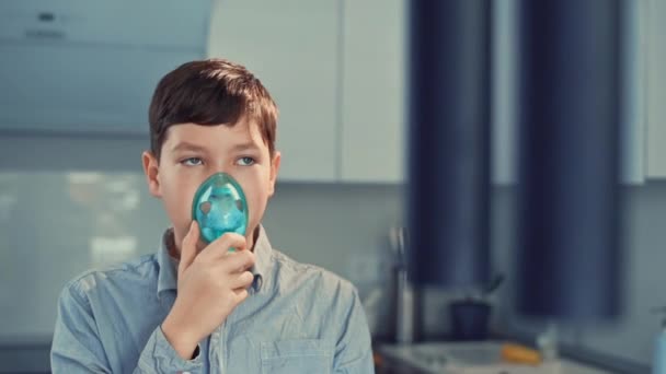 Leczenie astmy, chłopiec oddycha przez inhalator. Stojąc w kuchni - Materiał filmowy, wideo