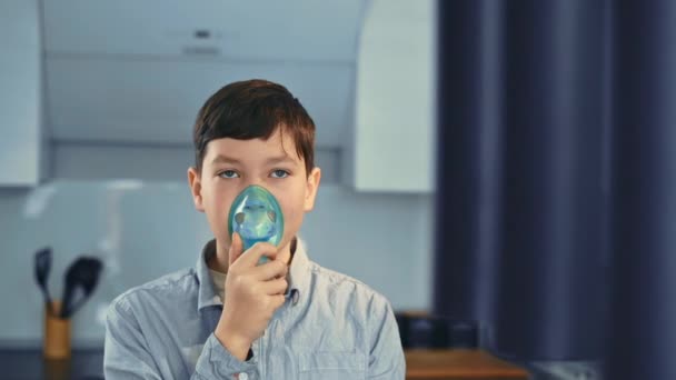 Treatment for asthma, the boy breathes through an inhaler. Standing in the kitchen - Footage, Video
