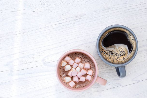 Mug of hot chocolate with small marshmallows next to a mug of bl - Photo, image
