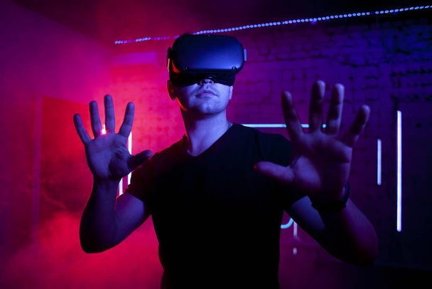 chico brutal serio con gafas VR se encuentra en la sala de realidad virtual y juega con joysticks, jugador masculino, mundo virtual
 - Foto, imagen