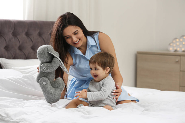 Niñera joven y lindo bebé jugando con juguete en el dormitorio
 - Foto, imagen