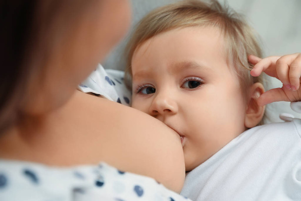 Vrouw borstvoeding haar kleine baby thuis, close-up - Foto, afbeelding