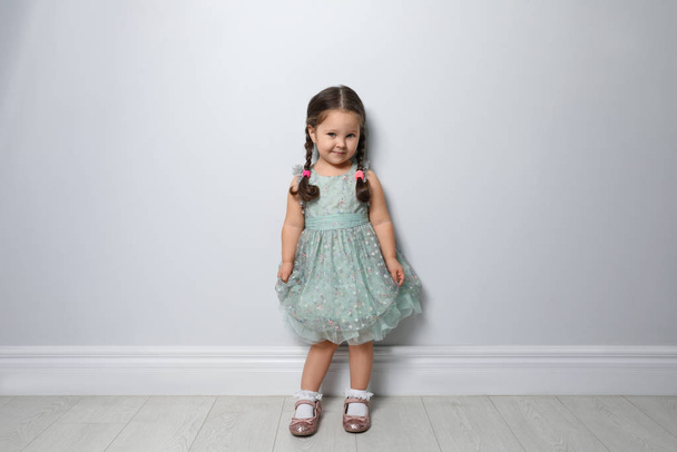 Cute little girl near light grey wall - Фото, изображение