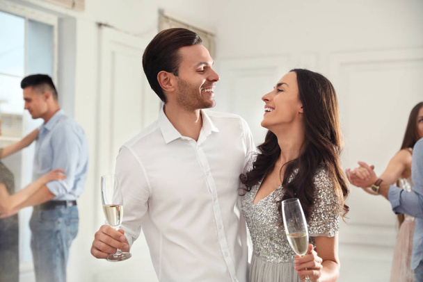 Lovely young couple with glasses of champagne at dancing party - Foto, Imagem