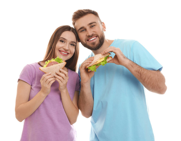 Young couple with tasty sandwiches on white background - Photo, image