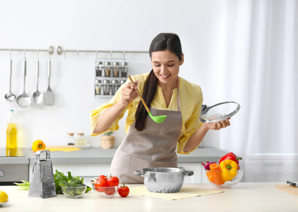 Young woman cooking tasty soup in kitchen - Photo, Image