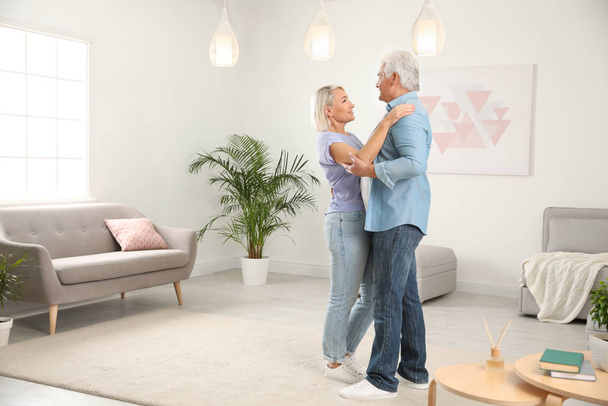 Onnellinen kypsä pari tanssia yhdessä olohuoneessa
 - Valokuva, kuva