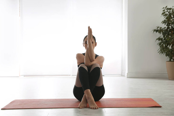 Woman practicing eagle asana in yoga studio. Garudasana pose - Zdjęcie, obraz