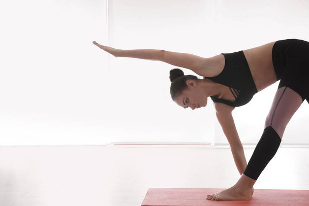 Young woman practicing extended triangle asana in yoga studio. Utthita Trikonasana pose - Photo, image