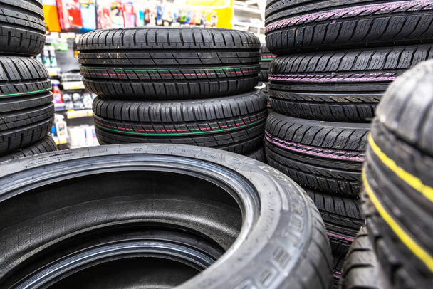Summer vehicle tires stacked up for sale at the store - 写真・画像