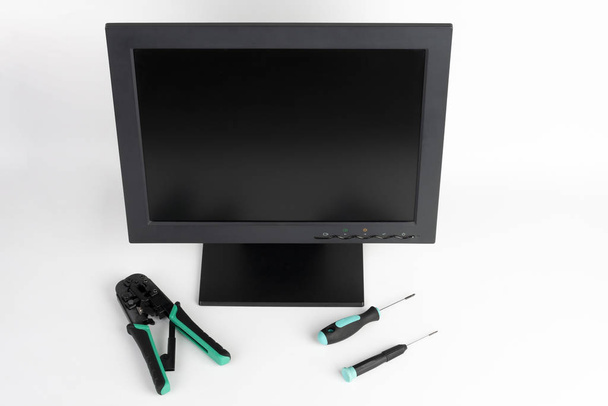 PC-LCD-Monitor mit Schraubendreher und Zange auf weißem Hintergrund  - Foto, Bild